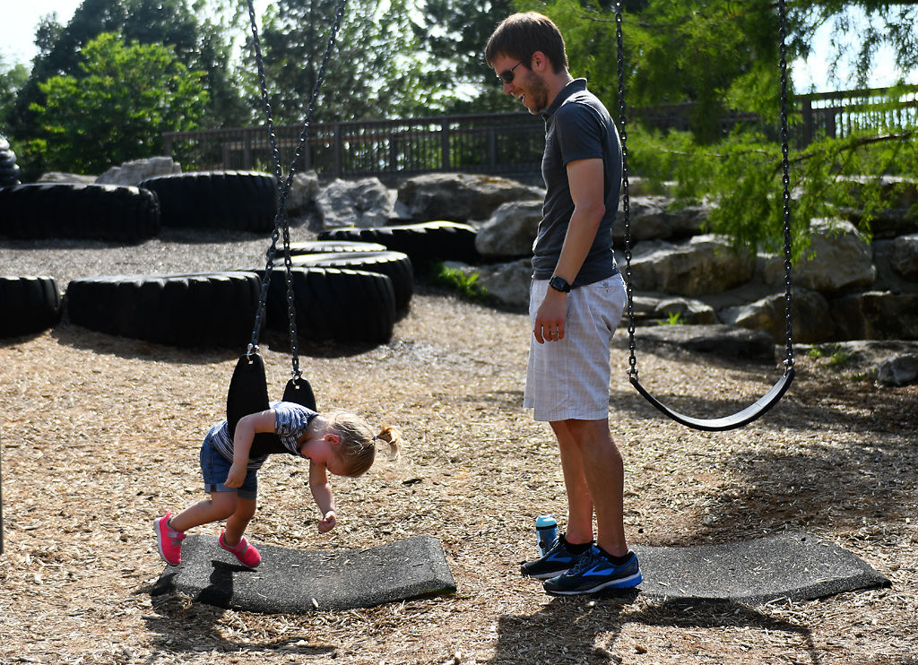 Brett Johnson and his daughter Lilly Johnson, 2, play on swing set